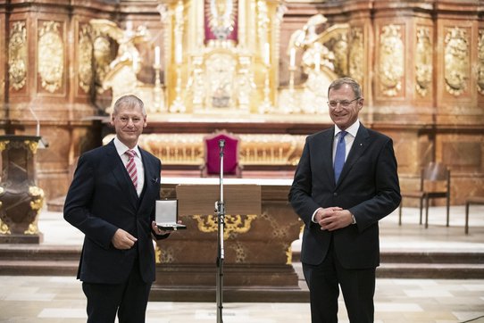 Franz Gruber hält das Silberne Ehrenzeichen des Landes OÖ in der Hand. Neben ihm steht Landeshauptmann Thomas Stelzer