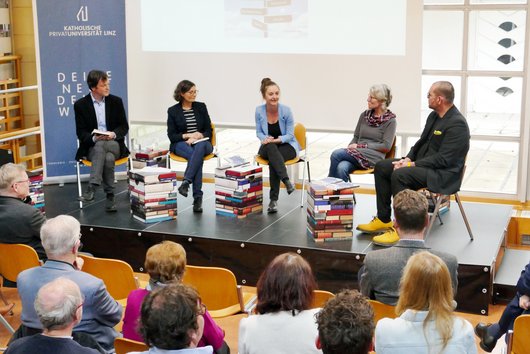 Moderatorin und die vier Autor:innen am Podium bei der Buchpräsentation in der Bibliothek der KU Linz.