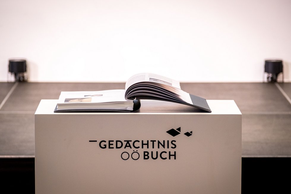 Aufgeschlagenes Buch auf einem Sockel mit dem Schriftzug "Gedächtnisbuch OÖ".