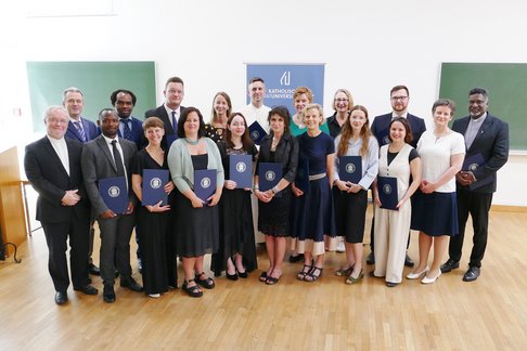 Verleihung akademischer Grade. © KU Linz/Eder. 15 Absolvent:innen der KU Linz mit Vizerektorin, Promotorin und den beiden Studiendekan:innen.