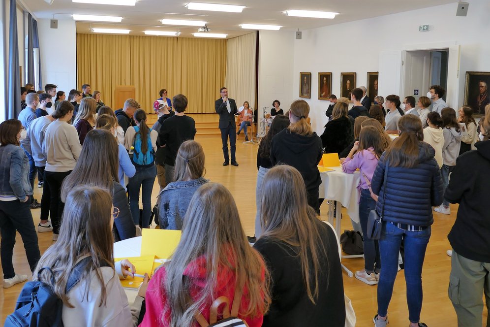 TheoTag 2022: Eröffnung in der Bischofsaula. © KU Linz / Hermine Eder. Regens Mag. Michael Münzner und Studienkoordinatorin Maria Gebauer begrüßen die Teilnehmer:innen in der Bischofsaula des Priesterseminars.